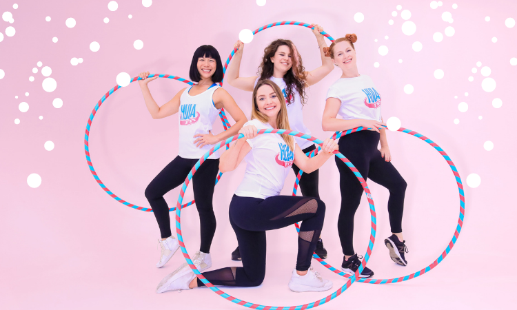 for women pose with hula hoops on a pink background. Snow graphics are artfully placed around them