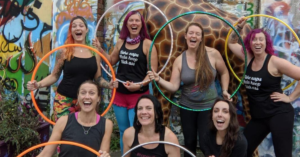 a group of white female hula hoopers posing happily with their hoops